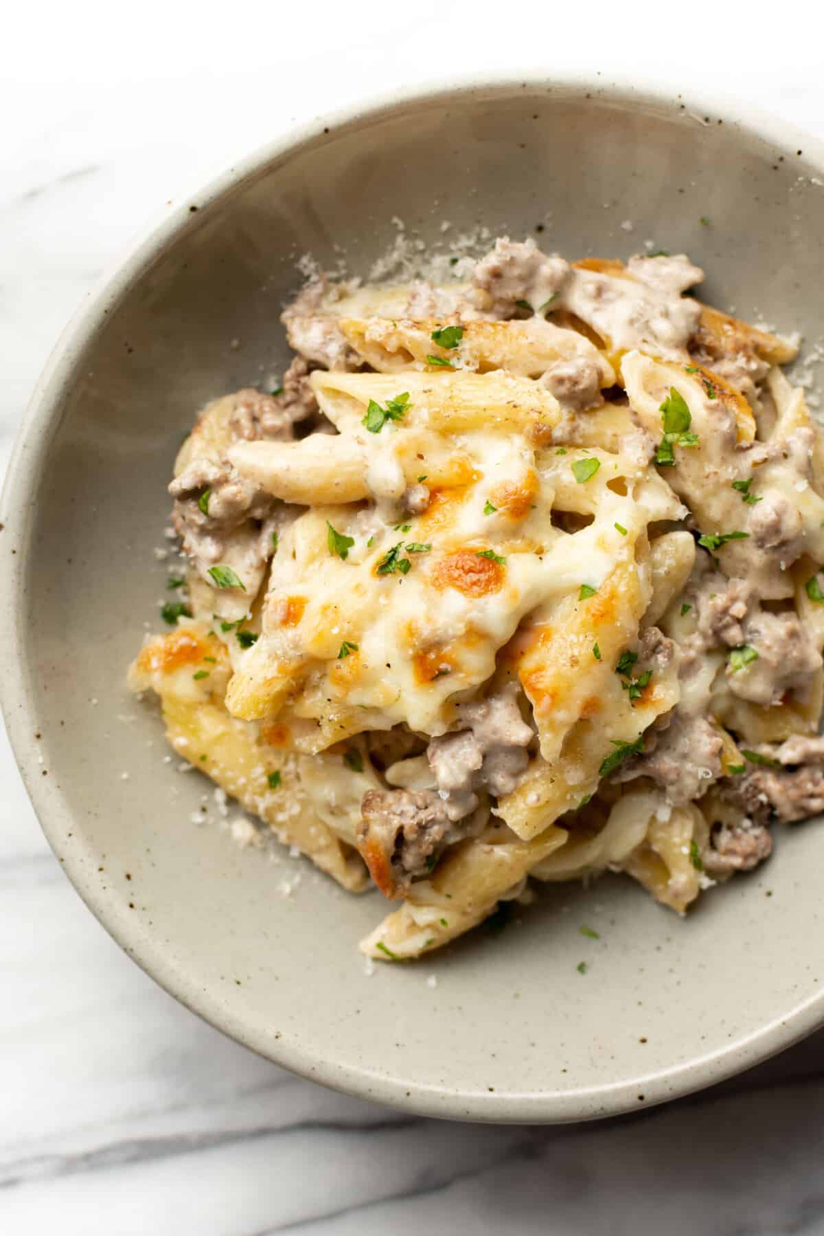 a bowl with a portion of cheesy ground beef Alfredo bake