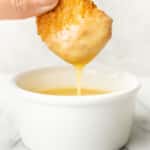 a female hand dipping a chicken nugget into honey mustard dipping sauce