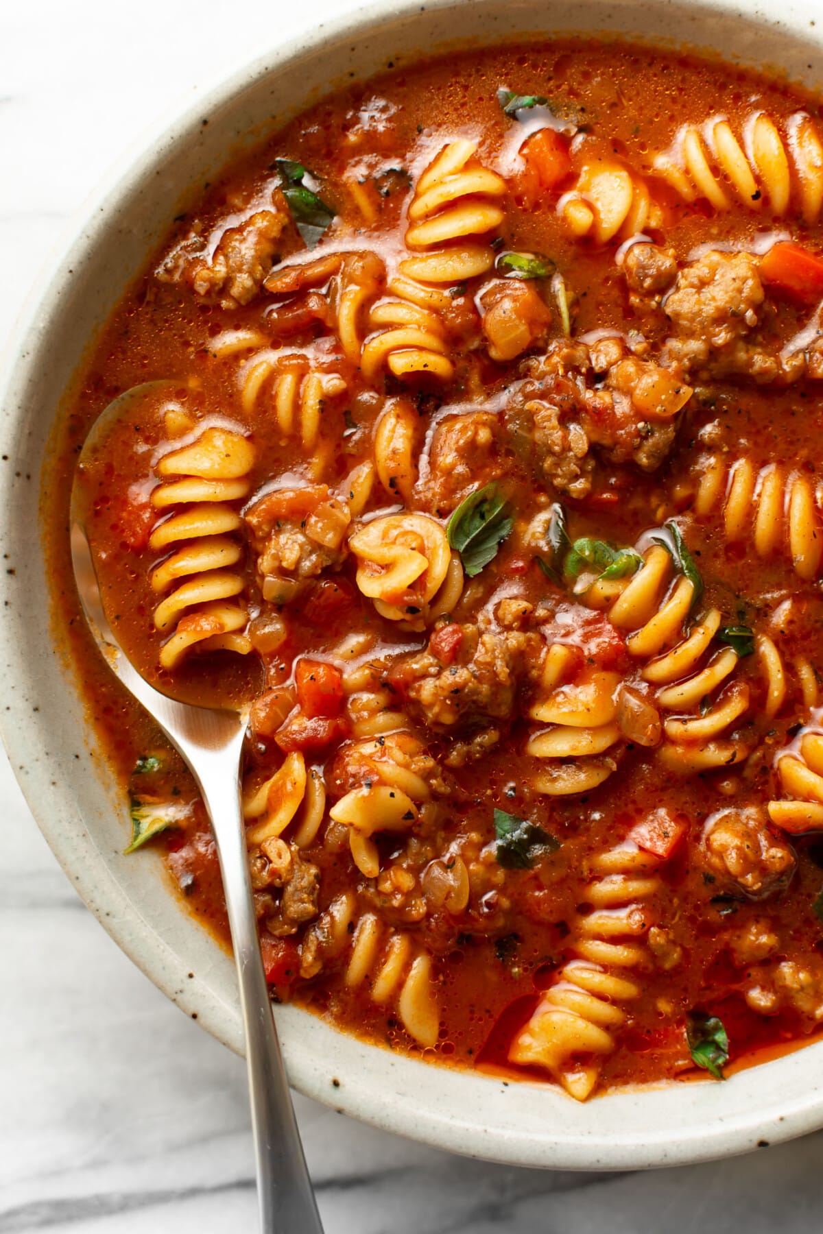 a bowl of italian sausage soup with a spoon