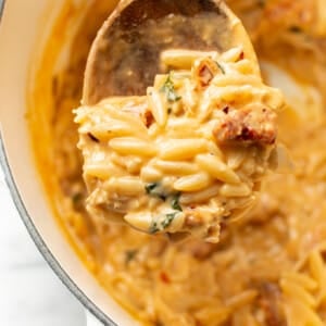 a dutch oven with marry me chicken orzo and a serving spoon