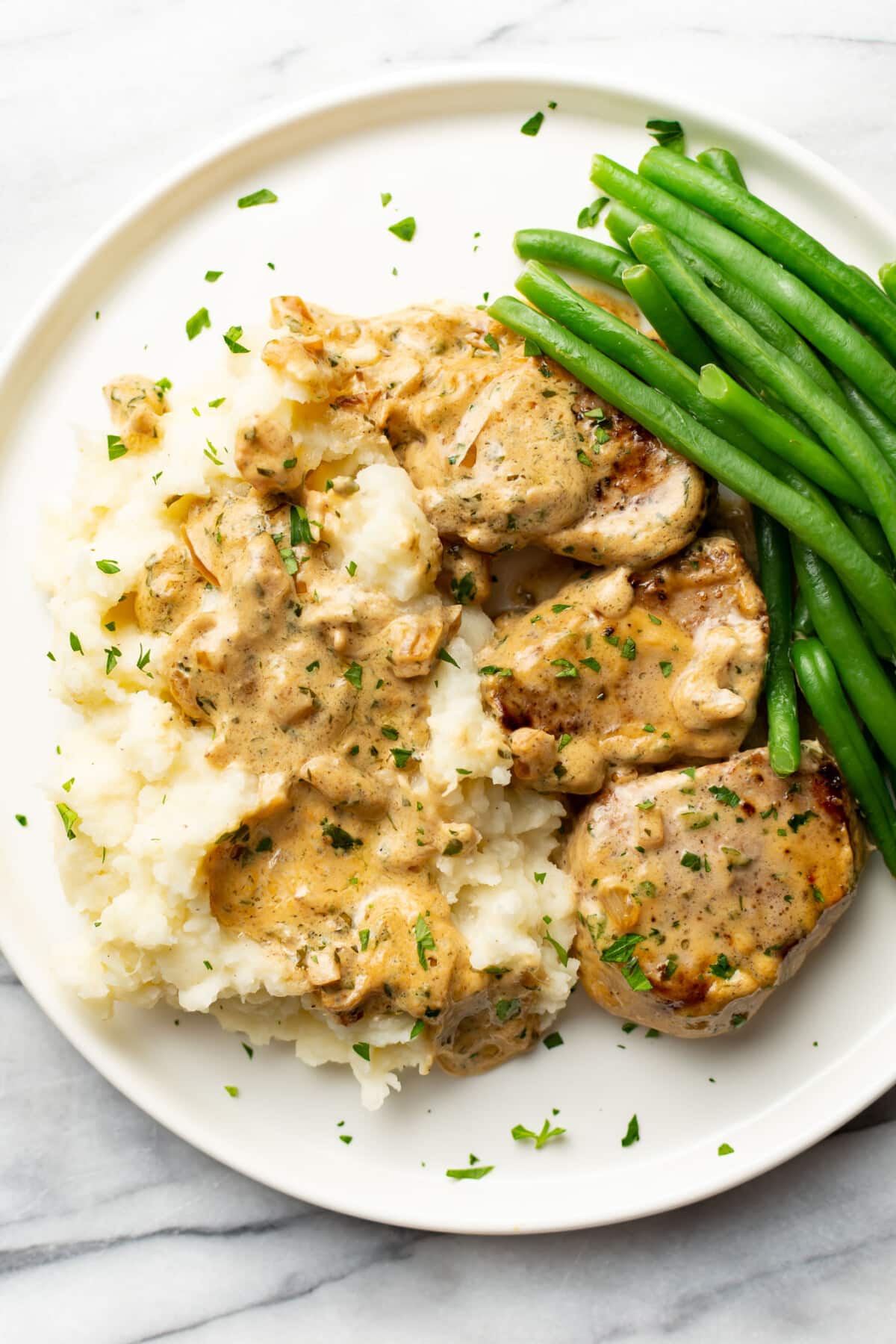 a plate with boursin pork tenderloin medallions, mashed potatoes, and green beans