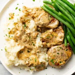 a plate with boursin pork tenderloin medallions, mashed potatoes, and green beans