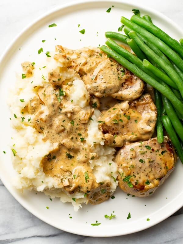 a plate with boursin pork tenderloin medallions, mashed potatoes, and green beans