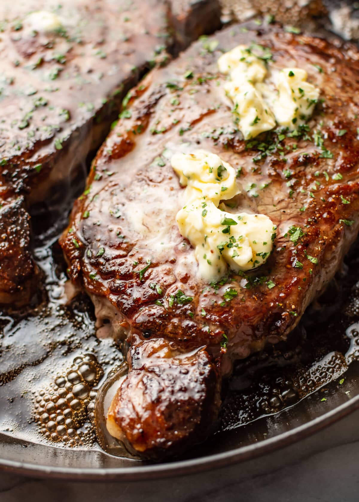 a plate with two ribeye steaks and butter on top