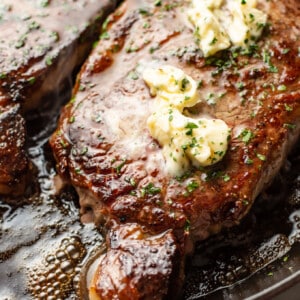 a plate with two ribeye steaks and butter on top