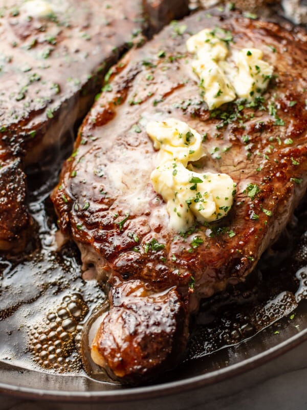 a plate with two ribeye steaks and butter on top