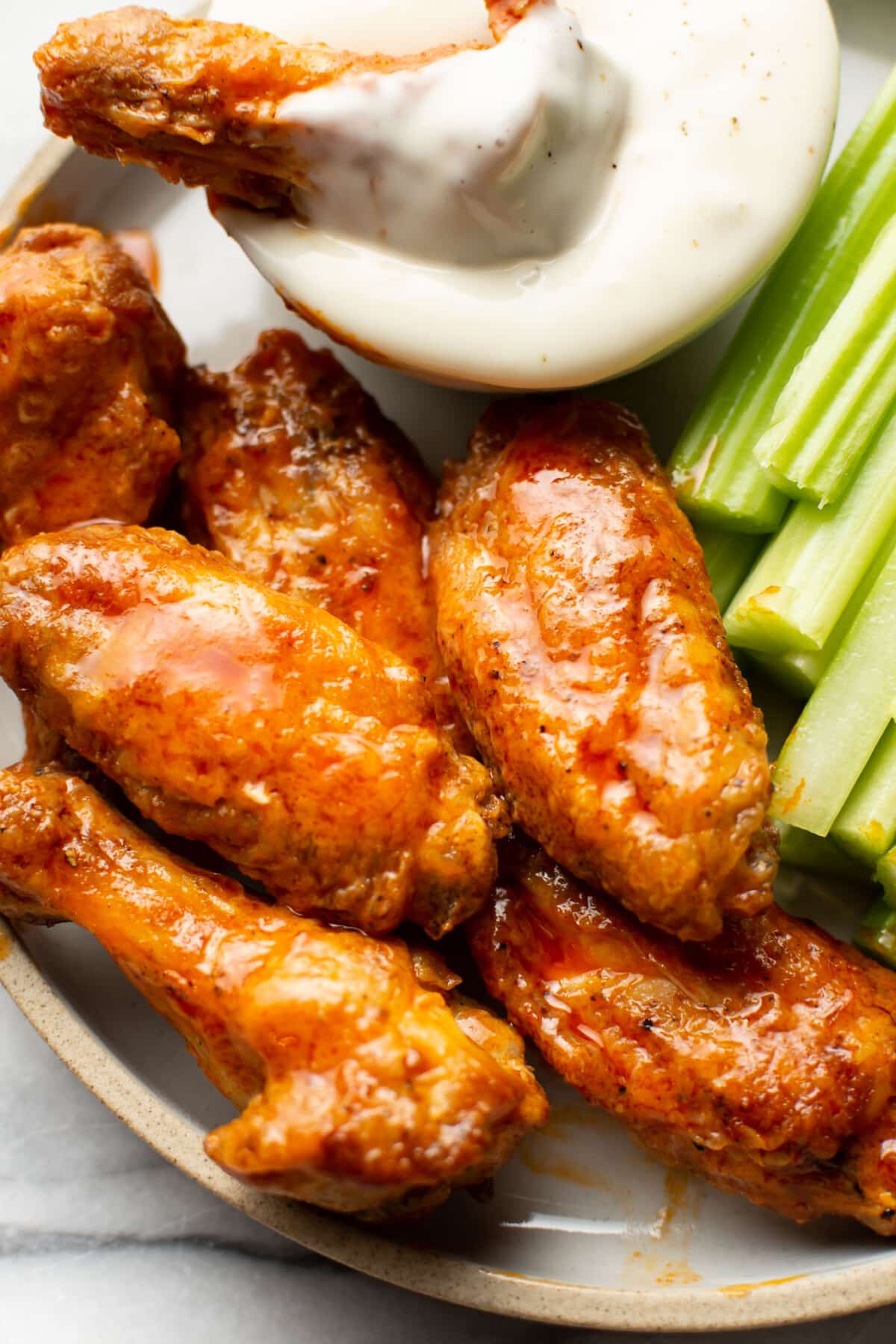 a plate of air fryer buffalo chicken wings with ranch dip and celery sticks