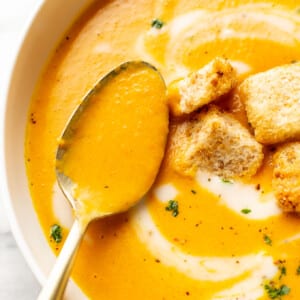 a bowl of carrot ginger soup with a spoon