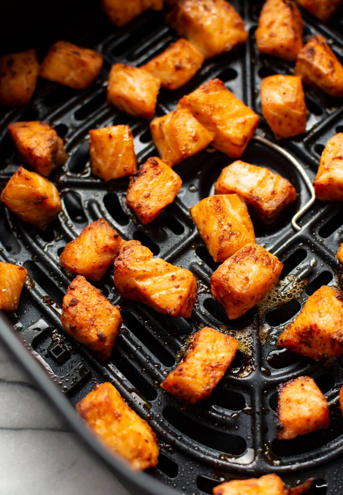 an air fryer basket with salmon bites