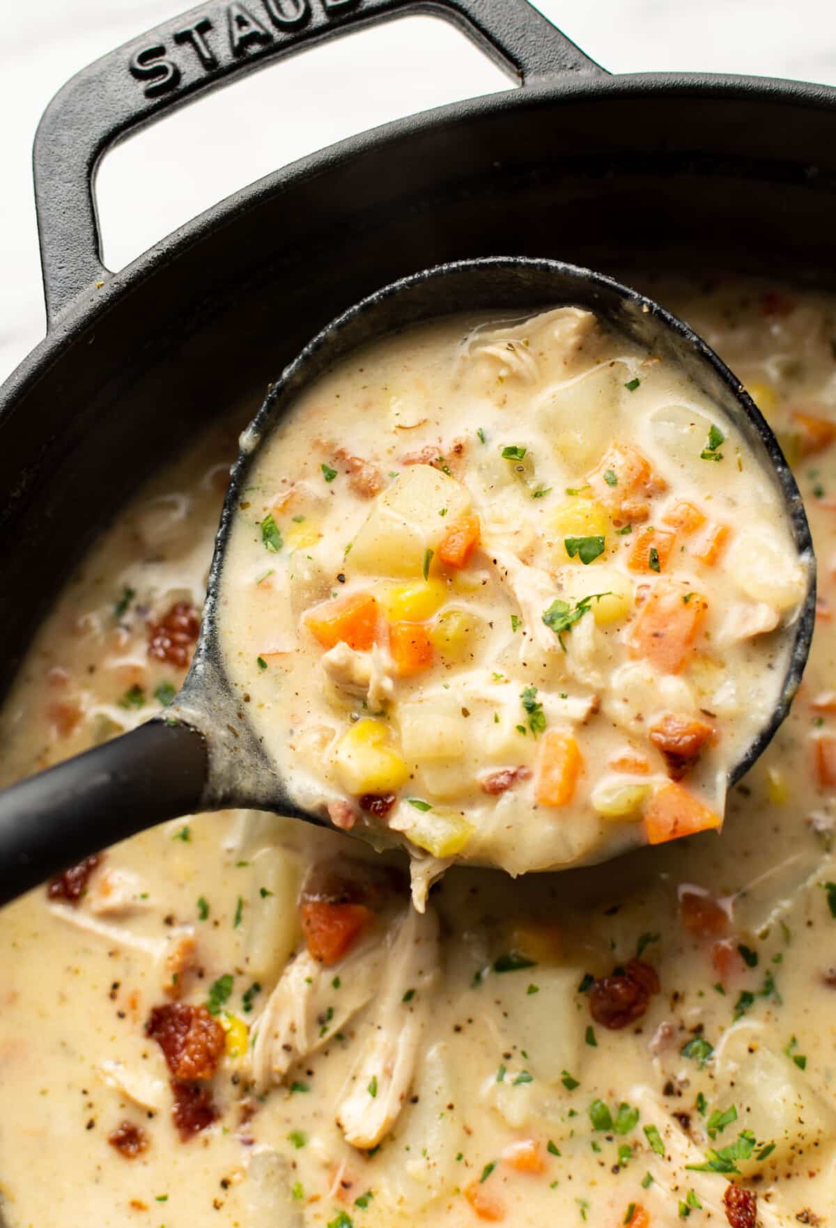 a ladle with creamy chicken and potato soup