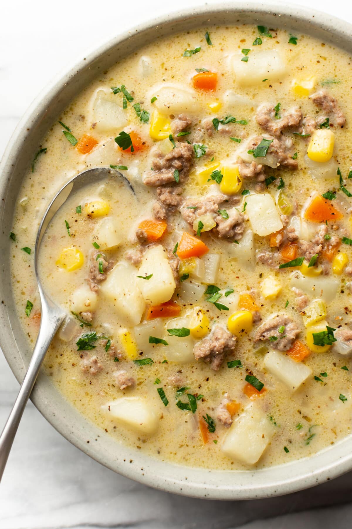 a bowl of creamy hamburger and potato soup with a spoon