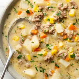 a bowl of creamy hamburger and potato soup with a spoon